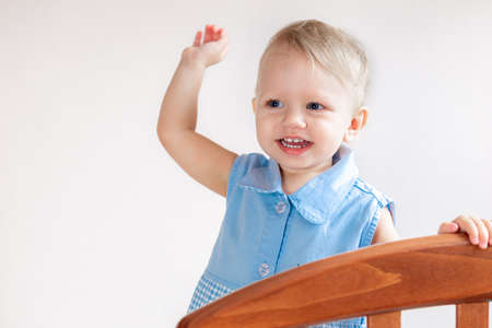 Little girl smiling looking out of the crib close-up.