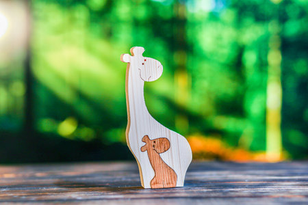 Wooden puzzle in the form of a family of handmade giraffes on the background of the forest.の写真素材