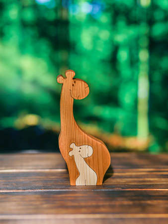 Wooden puzzle in the form of a family of handmade giraffes on the background of the forestの写真素材