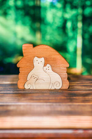 Wooden puzzle in the form of a cat family in a handmade house on the background of the forestの写真素材