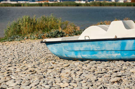 Blue boat on a pebble beach against the background of the sea.