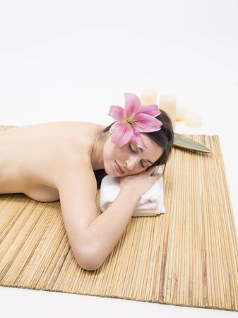 Relaxed young woman in a spa with candle and flowersの写真素材