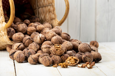 walnuts spilling from basket on white wooden table. walnut details