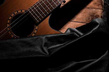 Guitar on a wooden background with a black satin.