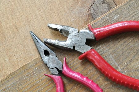 Two old rusty clamps rest on worn out table.の写真素材