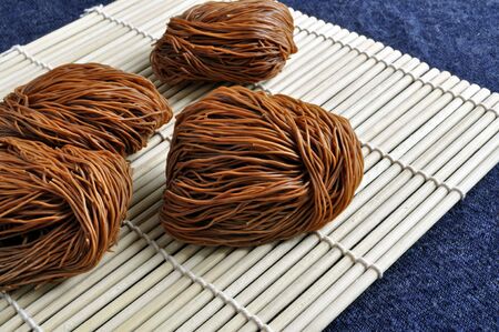 Pieces of dried noodles rest on a bamboo mat.の写真素材