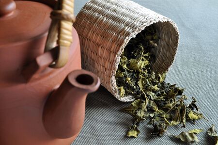 A basket of tea leaves with a clay teapot as foreground.の写真素材