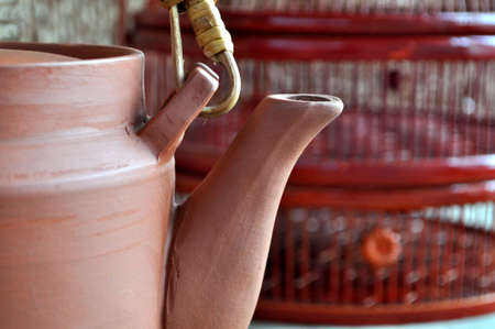 A clay teapot in front of a painted bamboo basket.の写真素材