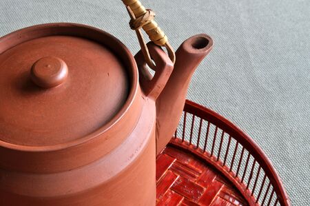 A clay teapot rest on a pained bamboo basin.の写真素材