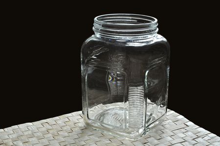 An empty wide mouth bottle made of glass rests on a grass mat.の写真素材