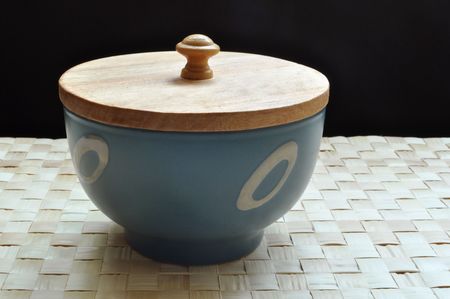 Blue bowl with wooden cover rests on a grass matの写真素材