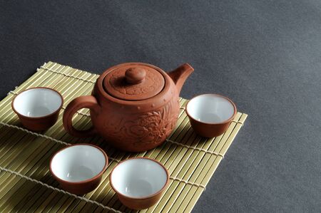 A set of Chinese tea drinking utensil rests on bamboo mat.の写真素材