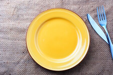 Top view of empty yellow ceramic plate on a sackcloth.の写真素材
