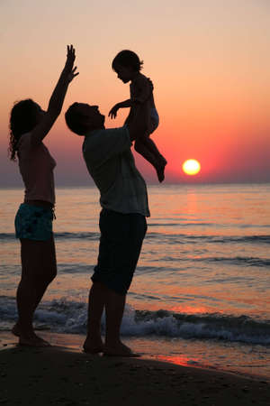 Mummy with daughter and grandfather on sunset at seaの写真素材
