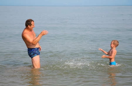 Grandfather with grandson sprinkle by water friend on friendの写真素材