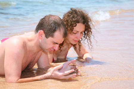 The woman and the man lay on sand at the seaの写真素材