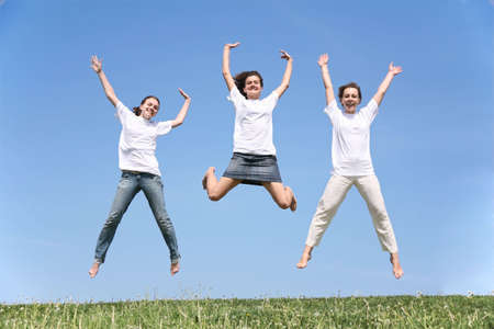 Three girlfriends in white T-shorts jump having waved handsの写真素材