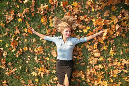 blue-eyed blond lies among yellow leaves