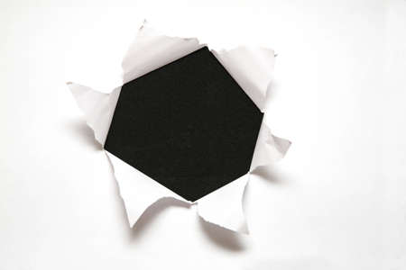 the sheet of paper with the hole against the black backgroundの写真素材
