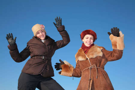 two young woman posing agains blue sky in winterの写真素材