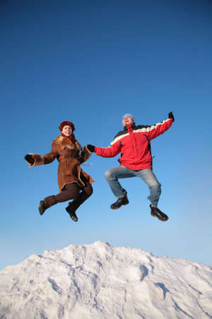 couple jump on top of snow hillの写真素材