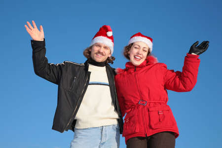 couple against blue sky background in winter in santa claus hats