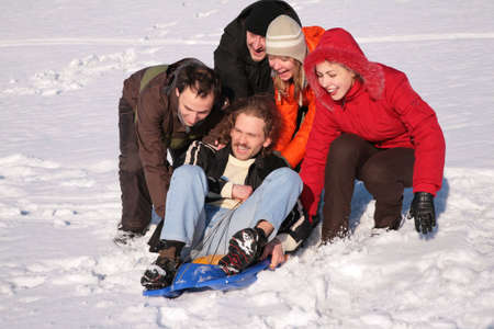 group of friends push another one on plastic sled