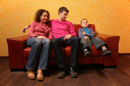 Family seating on red leather sofaの写真素材