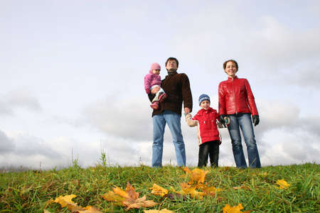 family stand on meadow at autumn