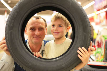 Boy and man look into vehicle tire in storeの写真素材