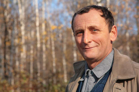 Portrait of elderly man in wood in autumnの写真素材