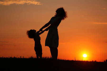 Mother and daughter on sunset watching on skyの写真素材