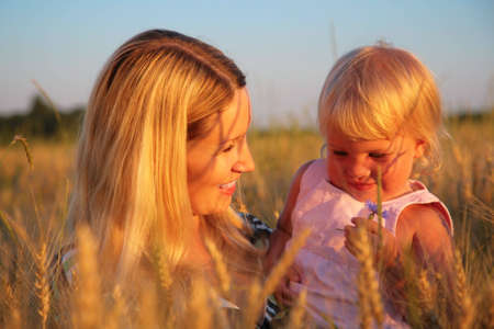Mother with child sit in wheaten fieldの写真素材