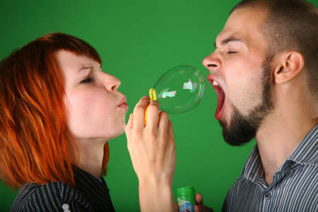 Girl with red hair blows soap bubble in mouth to guyの写真素材