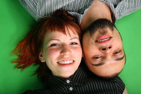 Girl with red hair and guy lie head to headの写真素材