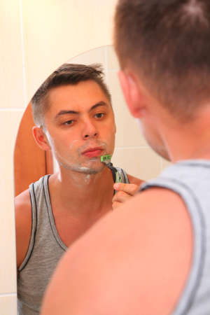 Man shaves against mirrorの写真素材