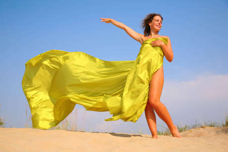 Young girl on sand in yellow fabric shawlの写真素材
