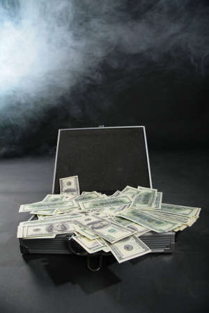 Suitcase with dollars against smokeの写真素材