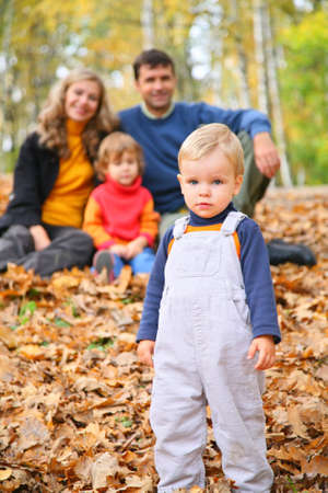 Little boy with family in forest in autumnの写真素材