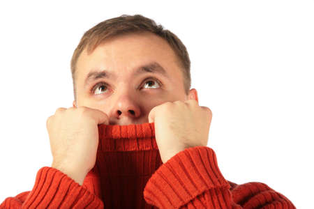 Pensive young man looks upward hiding in sweaterの写真素材