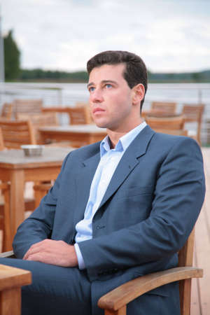 Portrait of man, who sits behind table in cafe near waterの写真素材