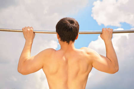 Athlete pull oneself up on sky backgroundの写真素材