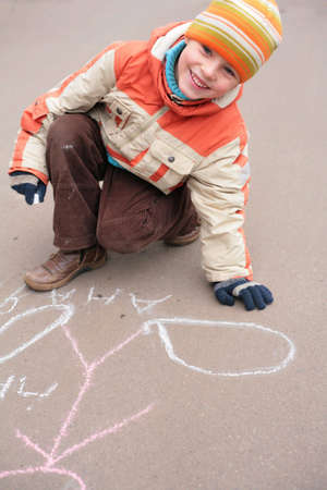 Boy drawing by chalk on asphaltの写真素材