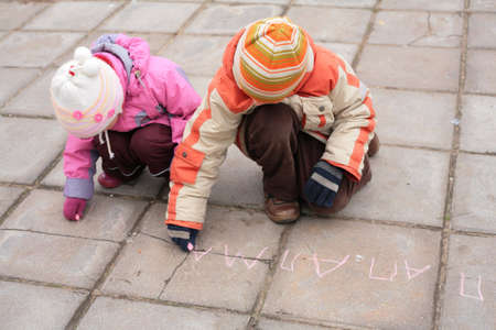 Two children with chalk on roadの写真素材