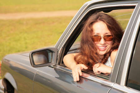 Woman smiles having turned back in a car window