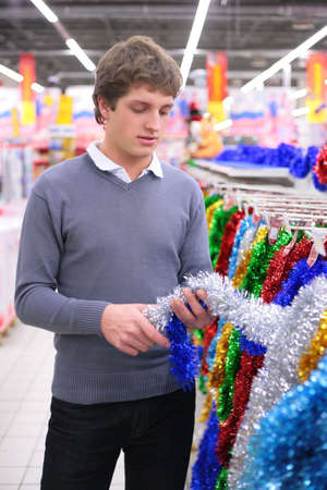 Young man chooses Christmas-tree decorationの写真素材