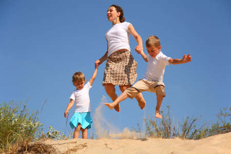 Mother with children jumping on sand