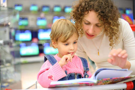 Mother and daughter looks in book in shopの写真素材