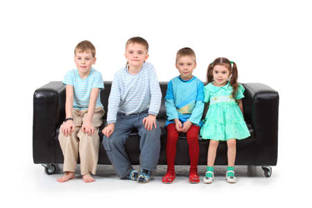 Four children sitting on black leather sofaの写真素材
