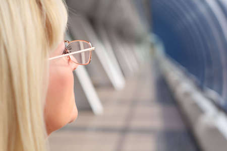 behind businesswoman in glasses on bridge closeup